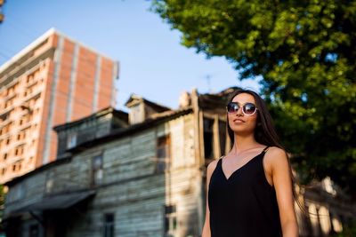 Portrait of smiling young woman standing against built structure