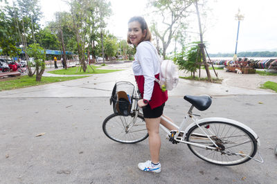 Portrait of young woman riding bicycle on footpath in park