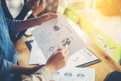 Midsection of business person with colleagues holding graph chart