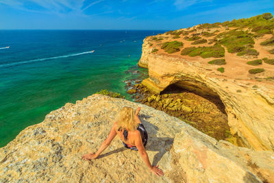 Woman sitting on rock against sea