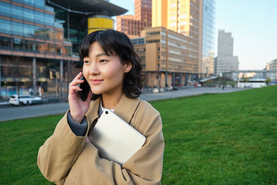 Young woman looking away while standing against buildings