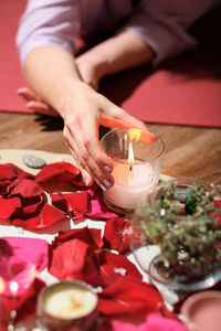 Woman holding  candle over flower petals during spiritual session. magic ritual, spiritual mystic