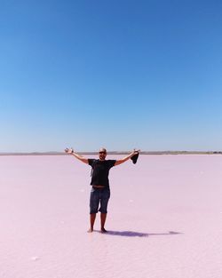 Portrait of man with arms outstretched standing at lake bumbunga against clear sky