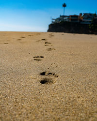 Footprints on sand at beach against sky