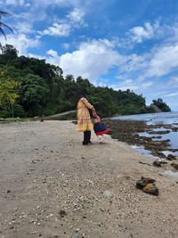 Rear view of woman walking on road against sky