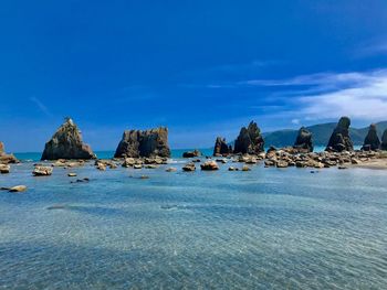 Rocks on beach against blue sky