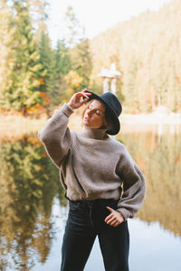 Young woman wearing hat standing by lake