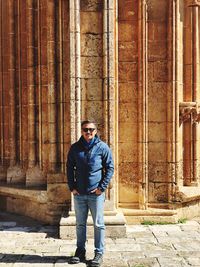 Portrait of young man standing against columns