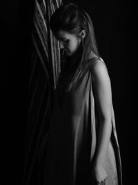 Young woman standing against black background