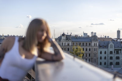 Portrait of woman in city against sky