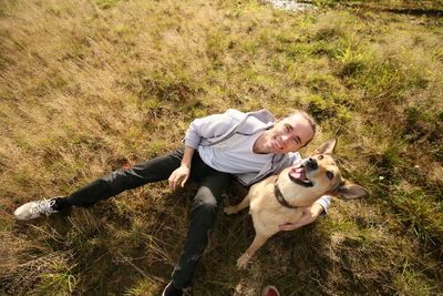 High angle view of man sitting with dog on field