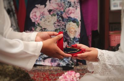 Cropped hands of bridegroom giving gold chain to bride during wedding ceremony