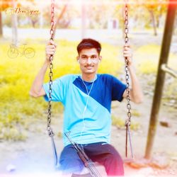 Portrait of smiling boy on swing at playground