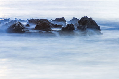 Rocks in sea against sky