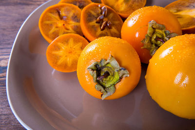 Persimmon cut into halves on a plate on a wooden table,copy space,closeup