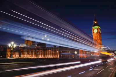 Light trails on road by big ben at night