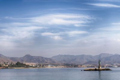 Scenic view of sea by mountains against cloudy sky