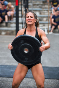 Mid adult woman lifting weights while standing outdoors