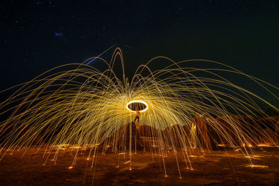 Illuminated ferris wheel against sky at night
