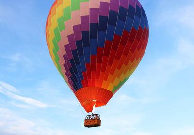 Low angle view of hot air balloon flying against blue sky