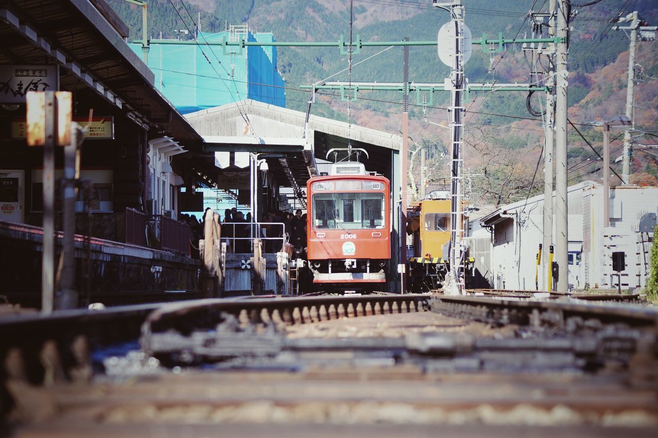 transportation, focus on background, architecture, built structure, city, mode of transport, railroad track, public transportation, building exterior, connection, cable, selective focus, day, surface level, outdoors, city life, development, tram, no people, journey, semi-truck