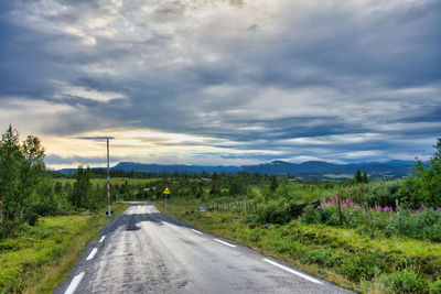 Road amidst field against sky