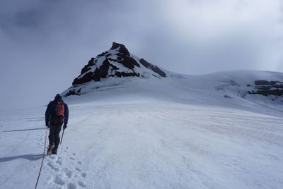 Rear view of man on snowcapped mountain against sky