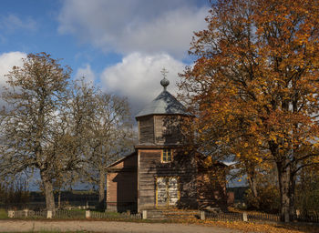 Trees by building against sky during autumn