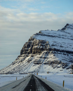 Road by snowcapped mountain against sky