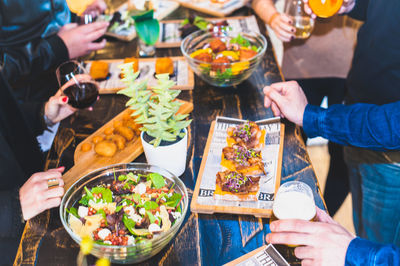 Midsection of friends with various food at table in restaurant