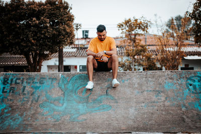 Portrait of young man sitting on fountain