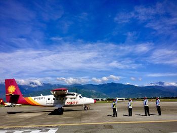 People at airport runway against sky