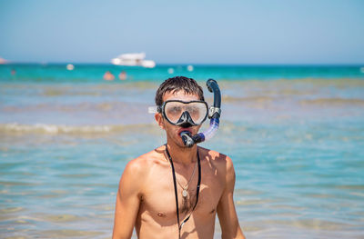 Portrait of young woman wearing sunglasses while standing at beach