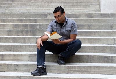 Low angle view of man reading book on steps