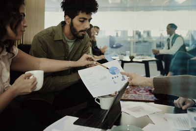 Group of business people analyzing charts during meeting in lobby