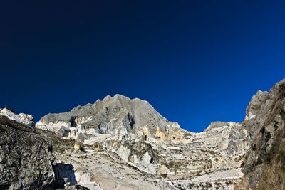 Low angle view of snowcapped mountains against clear blue sky