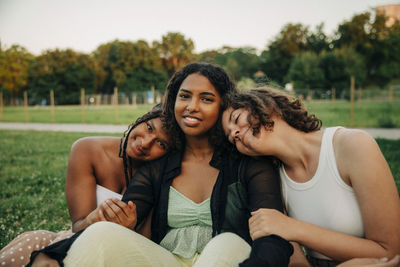 Portrait of teenage girl sitting amidst female friends at park