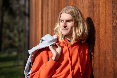 Happy european blonde guy smiling, look into distance relaxing outdoors enjoy sunny weather.