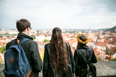 Rear view of friends standing against sky in city