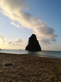 Rocks on beach against sky during sunset