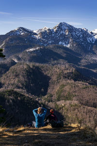 People sitting on mountain against sky