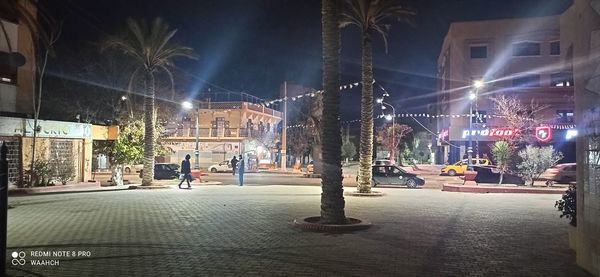 Illuminated street amidst buildings in city at night