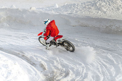 Motorcycle racer on motorcycle riding snowy turn