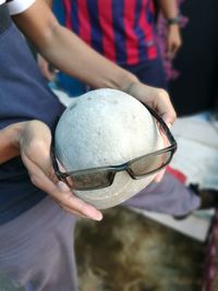 Midsection of man holding stone with sunglasses