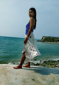 Woman standing at beach against clear sky