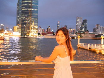 Portrait of young woman standing by railing