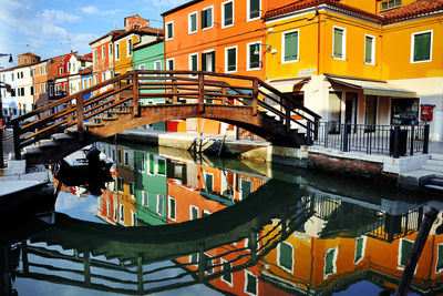 Arch bridge over canal by residential buildings in city