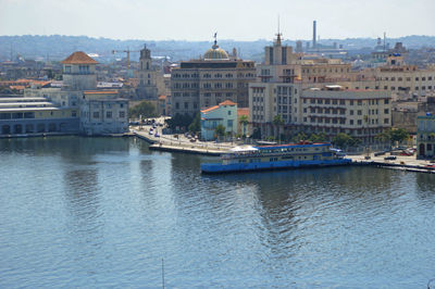Ferryboat in harbour against buildings in city