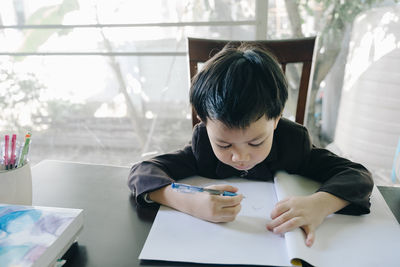 Boy holding mobile phone at table