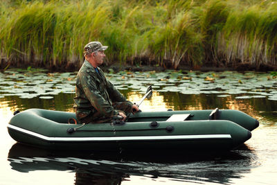 Side view of man sitting on boat in lake